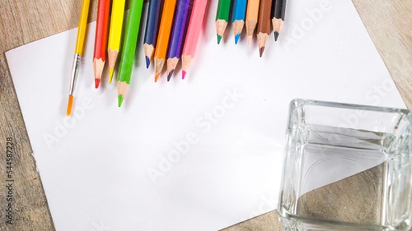 Fototapeta Colorful watercolor pencils and brushes on a white background. View from above.