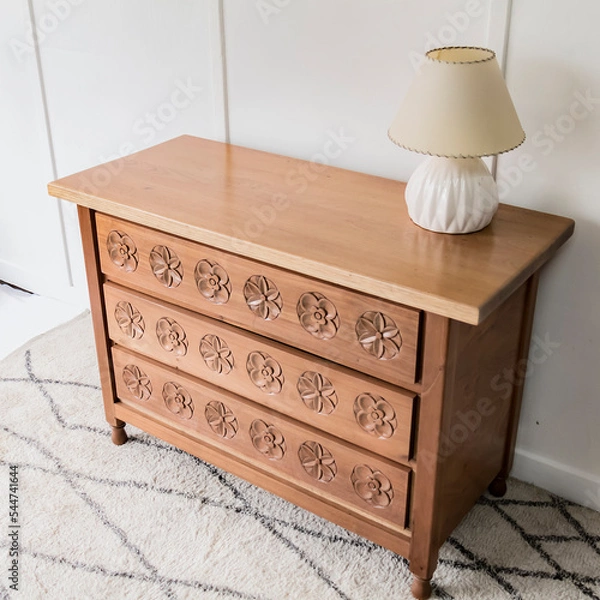 Obraz High angle view of a quaint and beautiful chest of drawers standing alone in a room lit by natural light.
