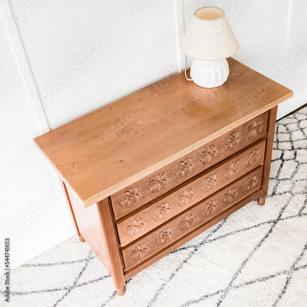 Obraz High angle view of a quaint and beautiful chest of drawers standing alone in a room lit by natural light.
