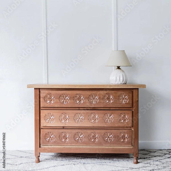 Obraz Front view of a quaint and beautiful chest of drawers standing alone in a room lit by natural light.
