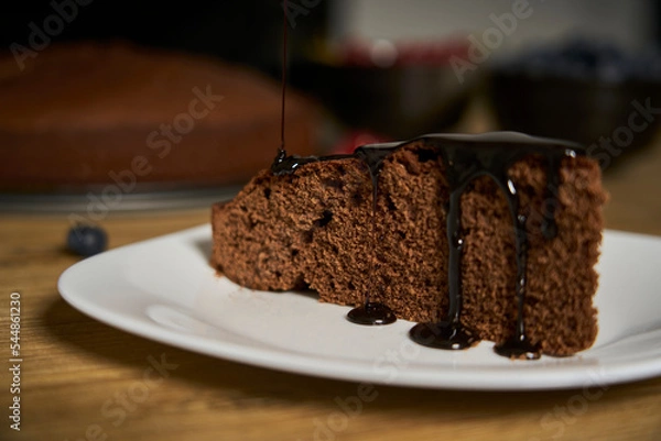 Obraz Handmade chocolate cake decorated with cranberries and red currants on the wooden kitchen table.