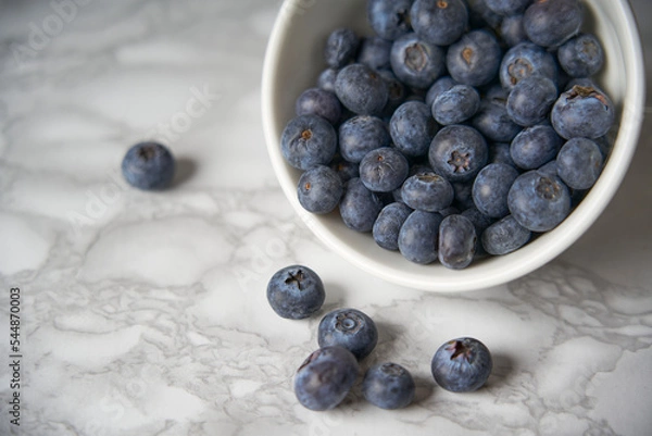 Fototapeta A group of fresh blueberries on a white and black marble table. 