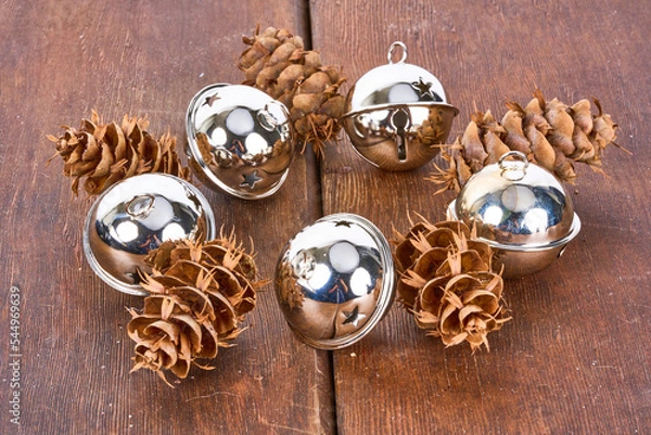 Fototapeta christmas bells and pinecones on wooden table  