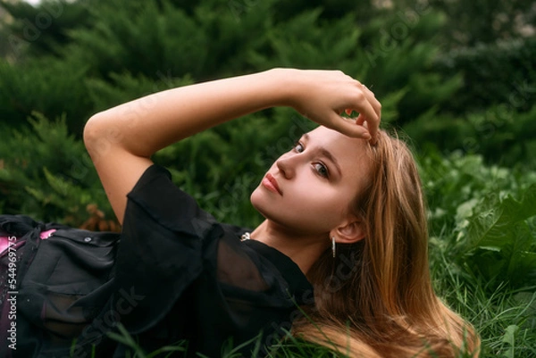 Obraz Fresh natural portrait of a cute blonde girl lying on the grass. Fashion snapshot of a beautiful young woman with clean skin, long blond hair and dark green eyes.