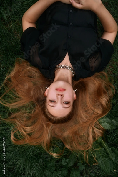 Obraz Fresh natural portrait of a cute blonde girl lying on the grass. Fashion snapshot of a beautiful young woman with clean skin, long blond hair and dark green eyes.
