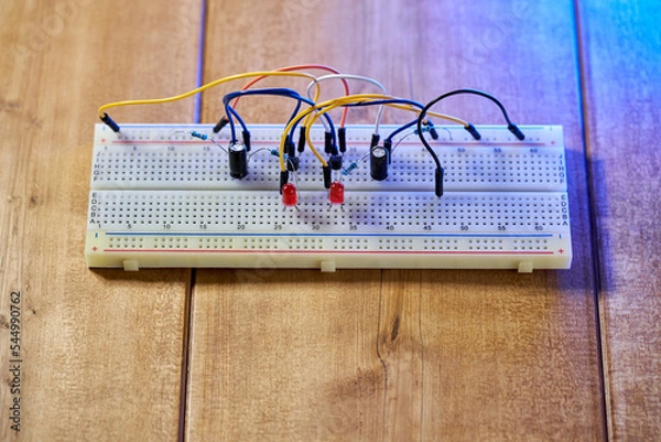 Fototapeta Breadboard with electrical elements, on a wooden table.