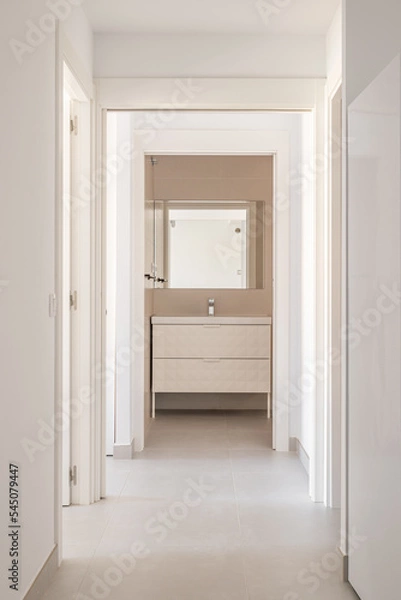 Fototapeta Bright corridor with white walls and tiled floor with a doorway to the bathroom
