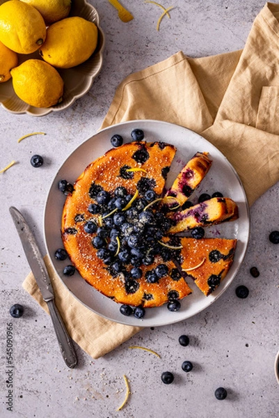 Fototapeta Sliced simple blueberry cake with lemons, top view on a plate 