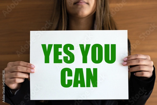 Fototapeta Yes you can. Woman holds a white page with green text. Inspiration, motivation, business, encouragement and the way forward.