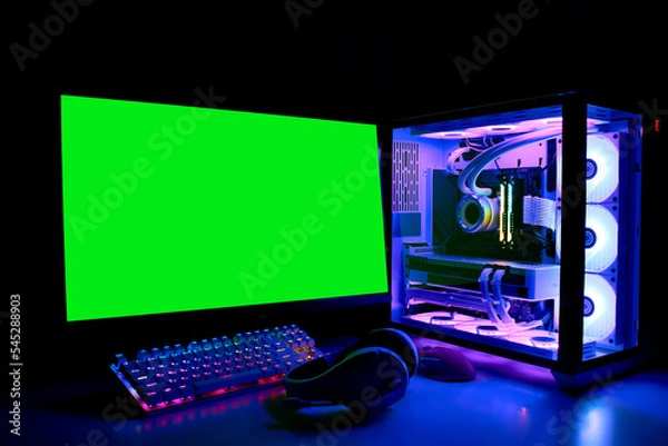 Obraz Gaming PC with RGB LED light, keyboard, mouse, headphones and monitor with green screen, copy space. Gamer's workspace. Modern powerful liquid-cooled Computer in a glass case