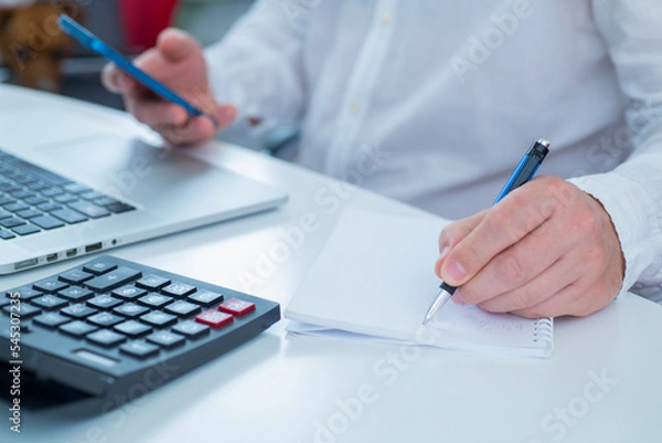 Fototapeta professional man uses calculator laptop and smartphone in office close up