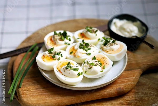 Fototapeta Boiled egg halves with mayonnaise and green onions.