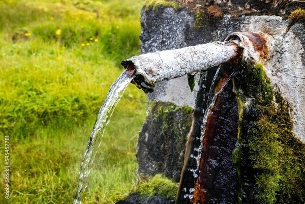 Fototapeta Closeup shot of water flowing from an old rusty pipe