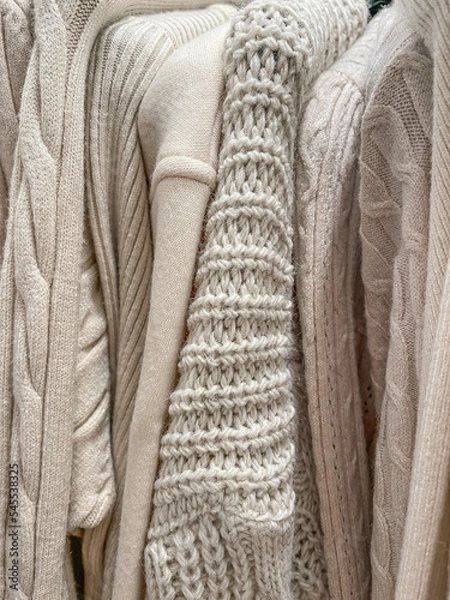 Fototapeta Soft cozy knit background photo of different knitted sweaters and jumpers of beige cream color.