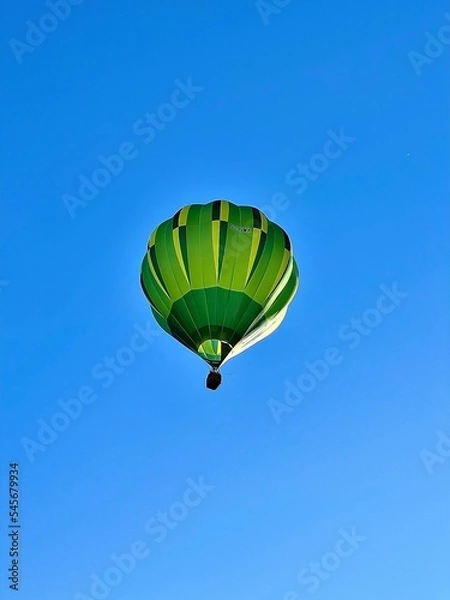 Fototapeta Mongolfiera verde in volo nel cielo blu