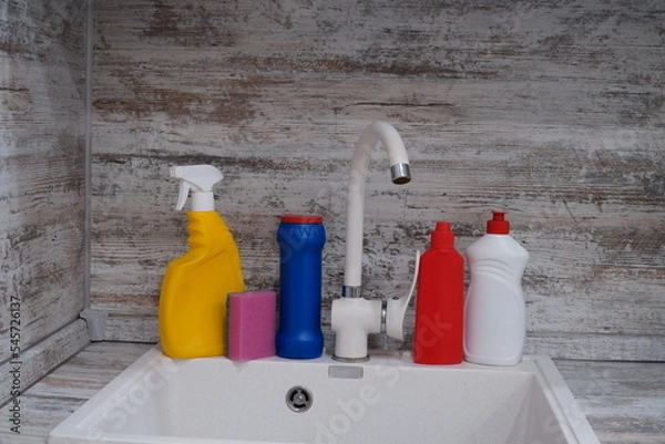 Fototapeta kitchen sink with bottles of cleaning products, Cleaning supplies and tools on the kitchen countertop