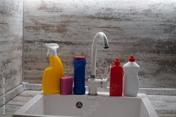 Fototapeta kitchen sink with bottles of cleaning products, Cleaning supplies and tools on the kitchen countertop