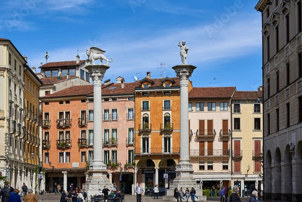 Fototapeta  Tourists stroll in Piazza dei Signori in Vicenza, in the background two ancient columns, the Column of the Redeemer and the Column of the Lion