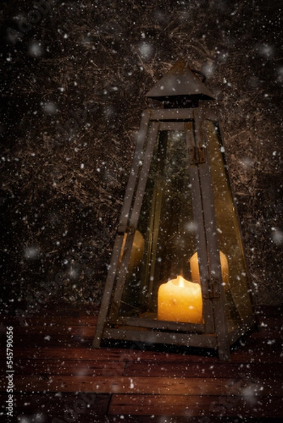 Obraz Old rusty lantarn. with a burning candle inside. during  beginning snowfall