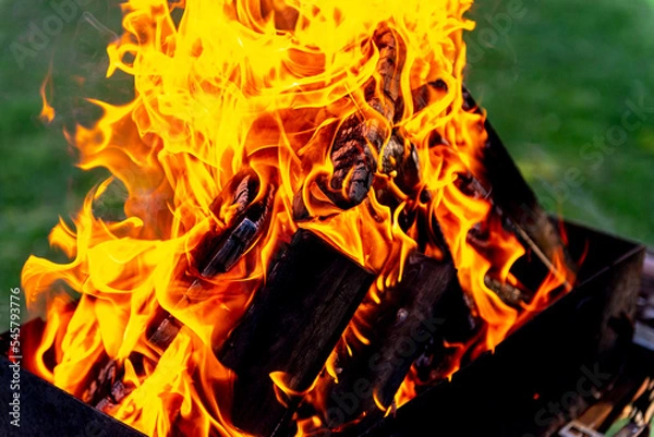 Obraz A large fire made of planks. Firewood in a bright flame. Firewood burns brightly in an iron grill.