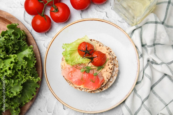 Fototapeta Crunchy buckwheat cakes with salmon, tomatoes and greens on white table, flat lay