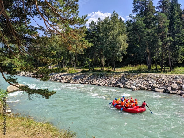 Fototapeta Arkhyz, Karachay-Cherkessia, Russia - August 26, 2022: Tourists go rafting. View of the Zelenchuk River in the village of Arkhyz against the backdrop of a coniferous forest