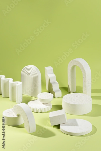 Fototapeta An empty stage with a composition of white podiums of different sizes and shapes on a green background and shadows