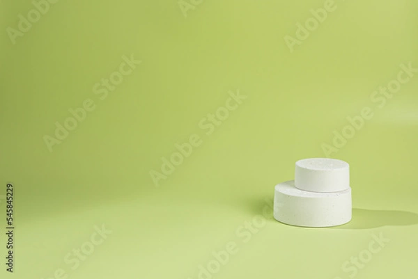 Fototapeta An empty stage with a pyramid of white podiums of top hats on a green background with a shadow from sunlight