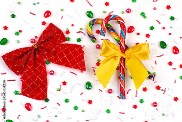 Fototapeta Christmas background of colorful candies, candy canes and bows, on a white background, close-up