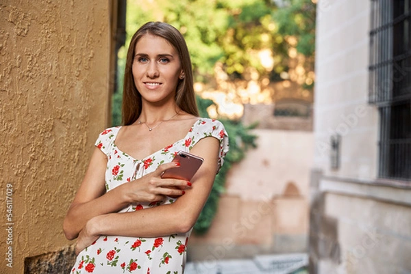 Obraz Blonde model posing and smiling with a phone in her hand.