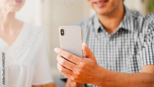 Fototapeta スマートフォンを一緒に見るミドル男性とミドル女性