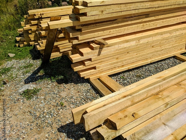 Fototapeta Wooden boards stacked in rows and lie on the ground. Boards for construction are sawn with bars. Close-up