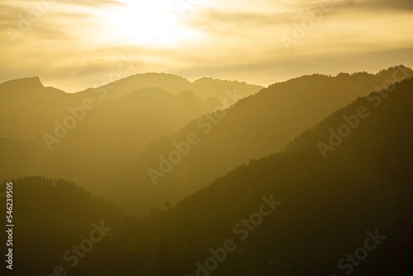 Fototapeta Spectacular view of mountain ranges silhouettes with yellow sunlight. Sunset in Allgau, Germany, Alps.