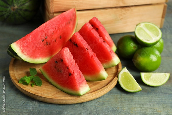 Fototapeta Slices of delicious watermelon, limes and mint on light blue wooden table