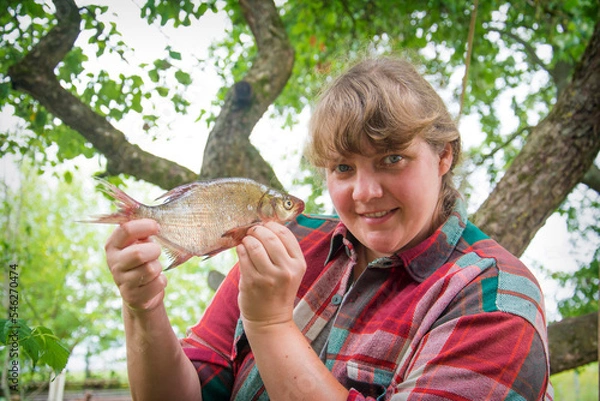 Fototapeta Large bream in women's hands. Girl on a fishing trip.
