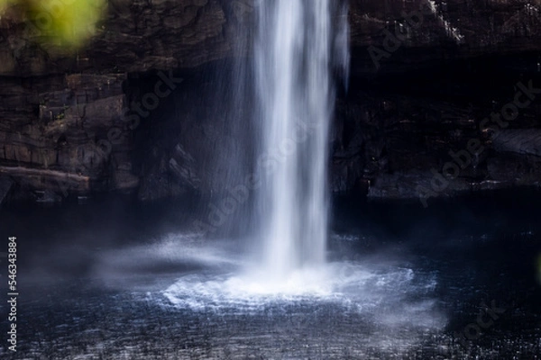 Fototapeta close-up of high waterfall plummeting into pool of freshwater below cave