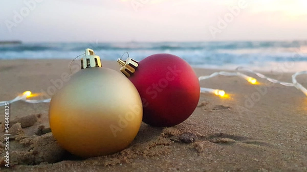 Obraz Christmas decorations in the form of a golden and red ball on the sand on the beach.