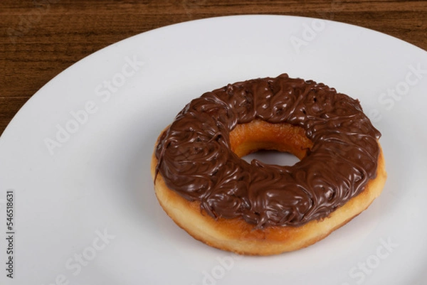 Obraz Tasty sweet donuts topped with chocolate and hazelnut cream served on a white plate. Close-up photograph with empty left side for texts.