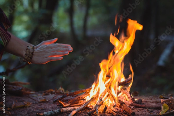 Obraz Close up hands warming over campfire concept photo. Make fire in forest. Side view photography with woman hands on background. High quality picture for wallpaper, travel blog, magazine, article