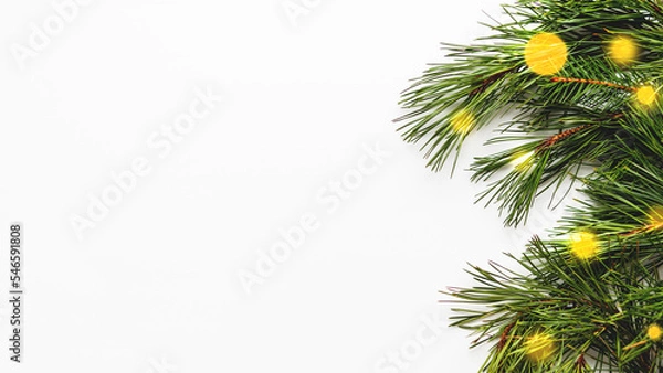 Obraz Festive banner with pine tree branches and light bulbs bokeh. White background with copy space and decorations for Christmas and New Year celebration.