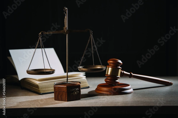 Fototapeta Justice and law concept.Male judge in a courtroom with the gavel, working with, computer and docking keyboard, eyeglasses, on table in morning light