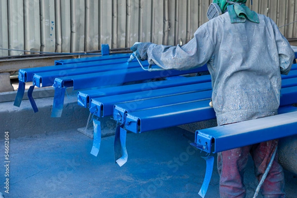 Fototapeta Paint Industry Steel Structure, The Painter is Working on Painting a Color Top Coat on a Steel Structure with a Spray Gun, at an Industrial Factory.