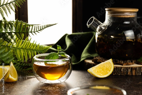 Fototapeta A glass mug with tea in the light is on the table. Custard tea with lemon