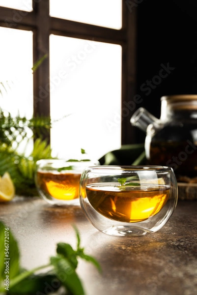 Fototapeta A glass mug with tea in the light is on the table. Custard tea with lemon