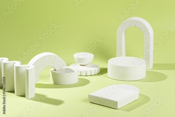 Fototapeta An empty stage with a composition of white podiums of different sizes and shapes on a green background and shadows