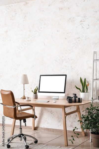 Fototapeta Photographer's workplace with computer and equipment near light wall