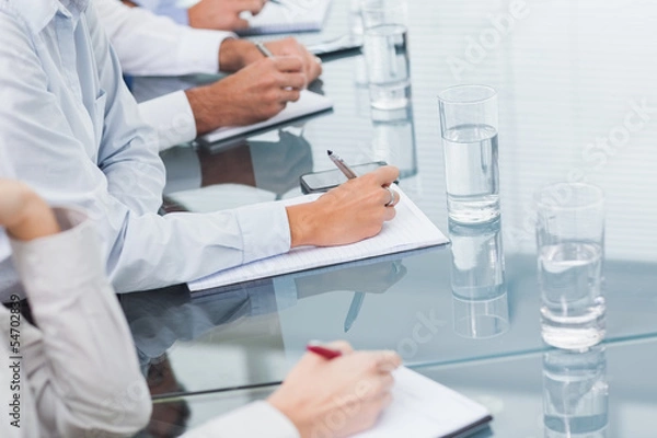 Fototapeta Close up on workmates hands taking notes during presentation