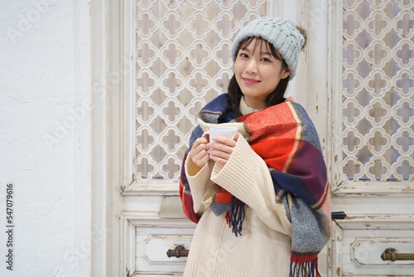 Obraz 温かい飲み物を持ってこちらを見る笑顔の女性