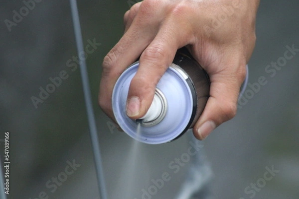 Fototapeta Closeup of man painting a fence with spray paint or aerosol paint