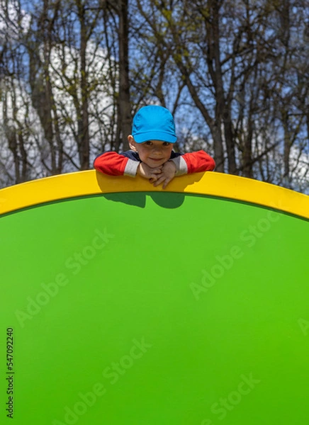 Fototapeta  portrait of a todler boy at the playground on a sunny spring day with space for text
